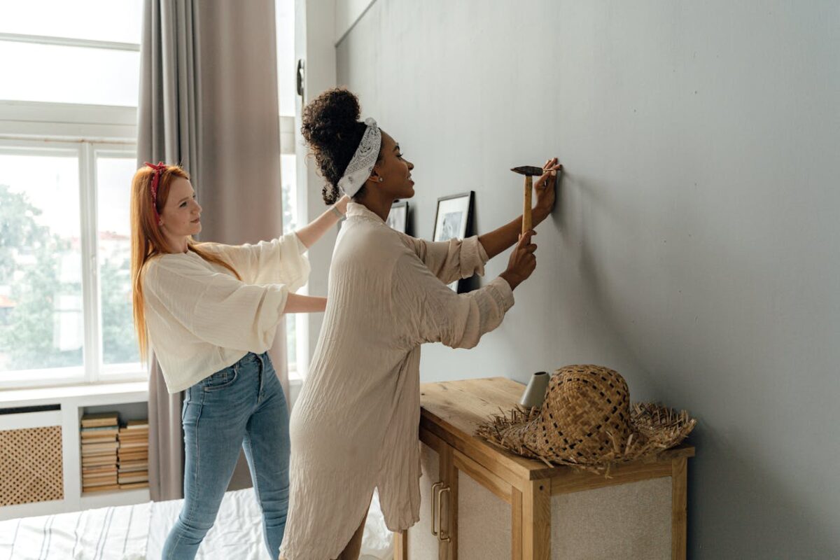 Two women in casual attire working together on home interior decoration.